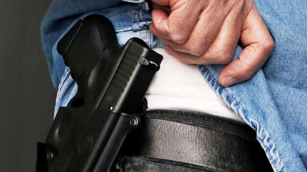 A man lifts his shirt to reveal a handgun carried in a hip holster on Feb. 27, 2013.