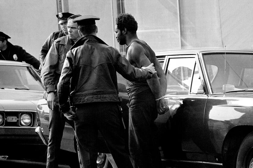 One of several men and women who surrendered to police after a siege of the Los Angeles Black Panthers headquarters is in police custody after the siege ended, Dec. 8, 1969 in Los Angeles. (AP Photo/Wally Fong)