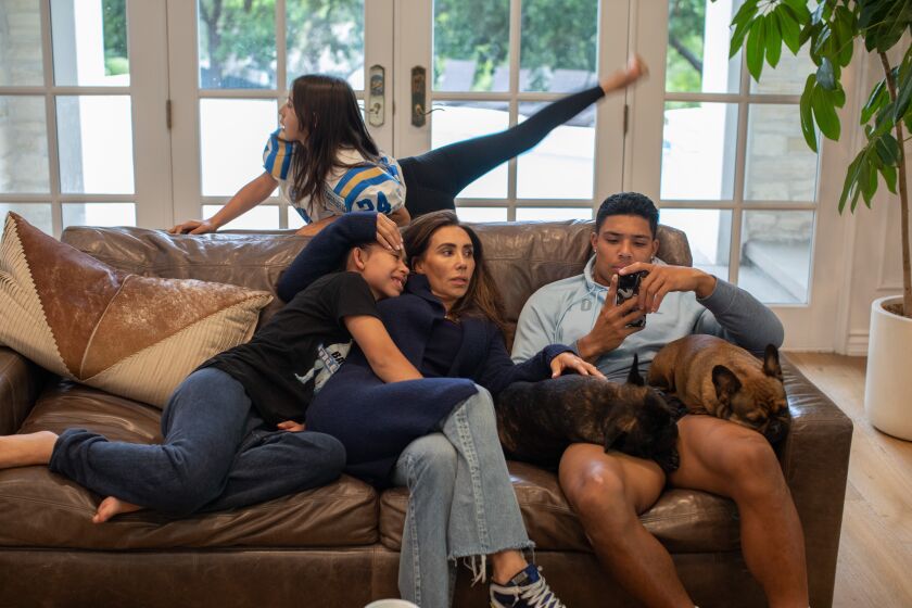 WESTLAKE VILLAGE, CA - OCTOBER 15: Zach Charbonnet, right, and his mother Seda Hall, sisters Bella, left, Athena, rear, working on her gymnastics moves, with napping Bosco and Bebe, look through a boba menu during a team bye week Saturday with the family. The UCLA running back chose UCLA to be closer to his family, especially his sister Bella who has special needs and who formed a close relationship with him. Photographed on Saturday, Oct. 15, 2022. (Myung J. Chun / Los Angeles Times)