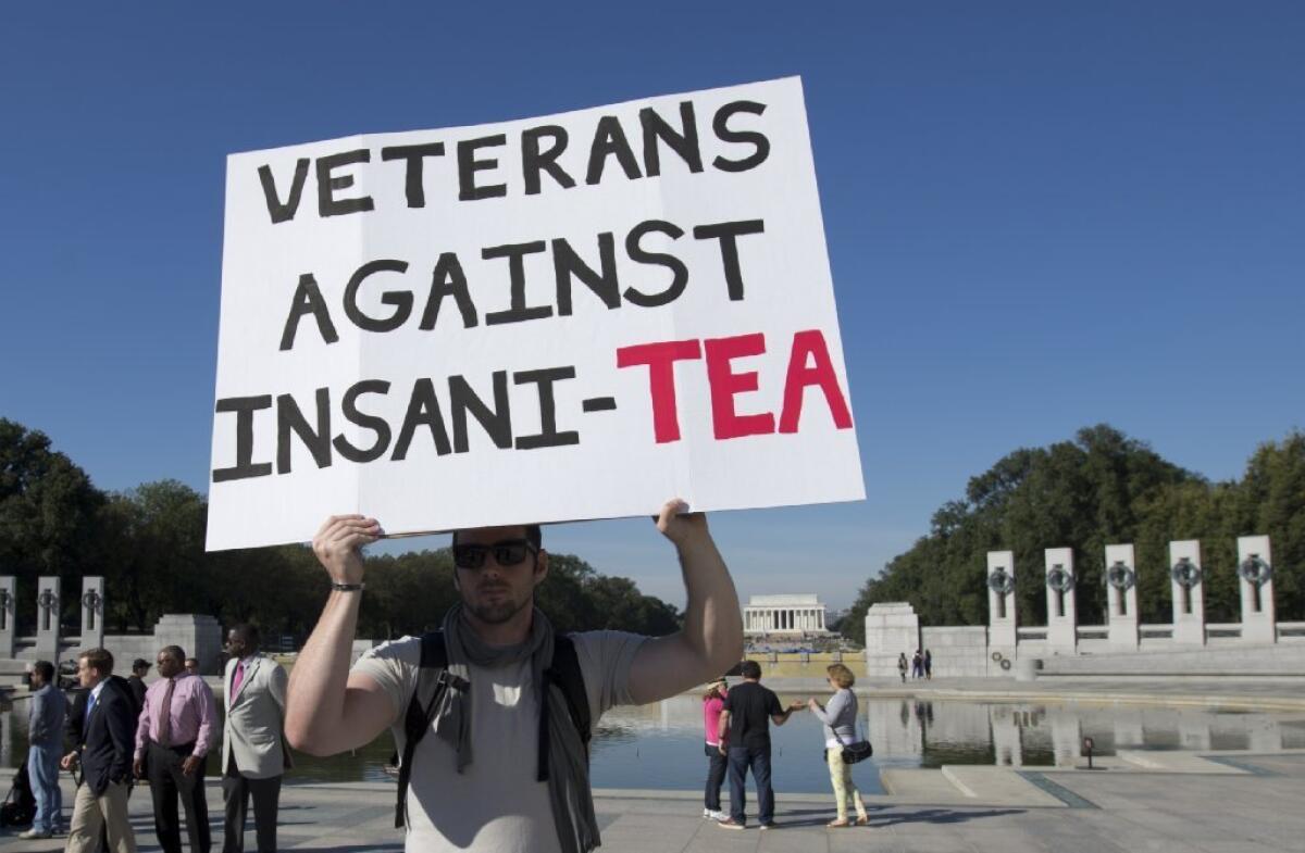A U.S. Army veteran walks with a sign during a rally at the National World War II Memorial on Tuesday to protest the government shutdown.