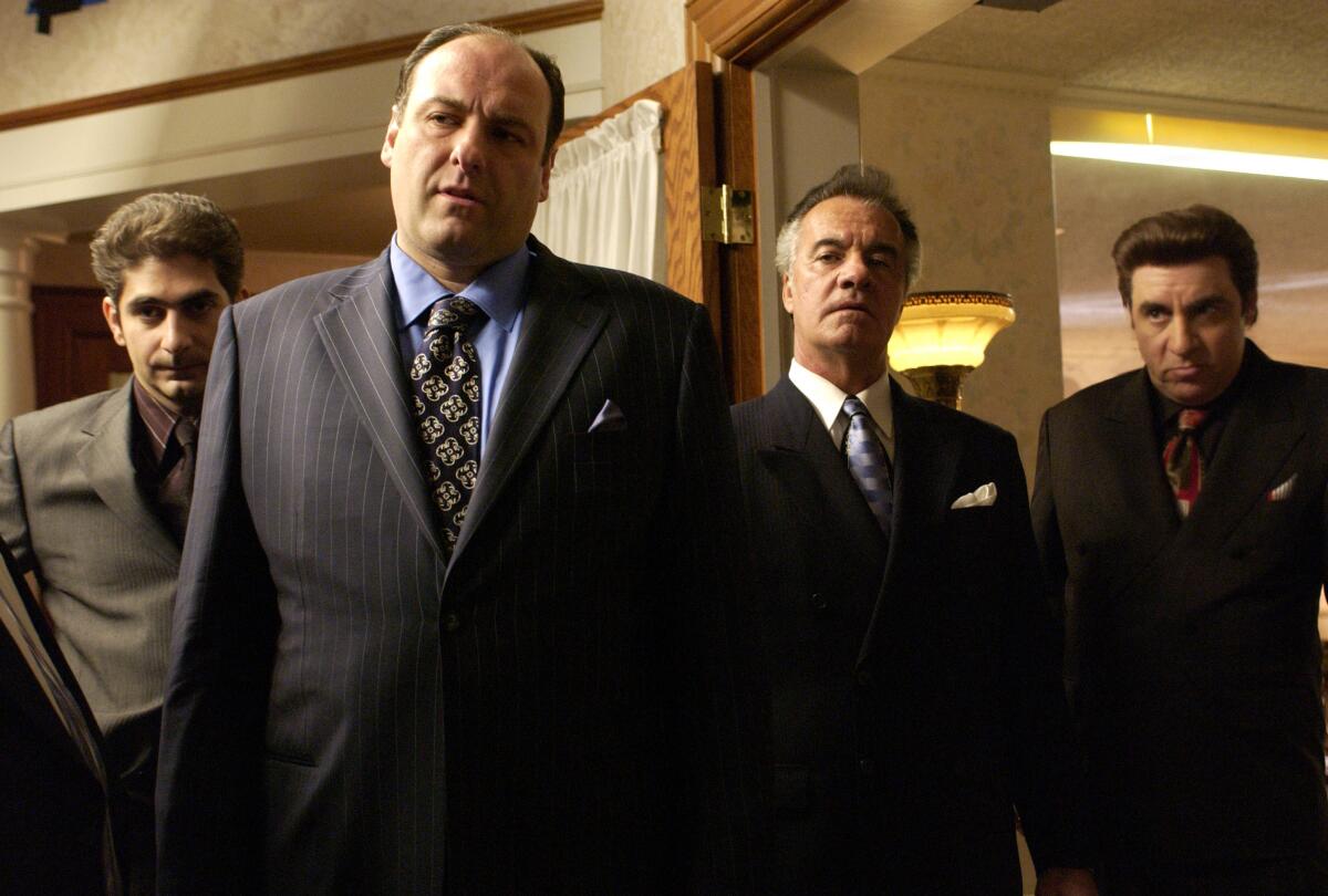 Four men in suits and ties stand in a parlor.