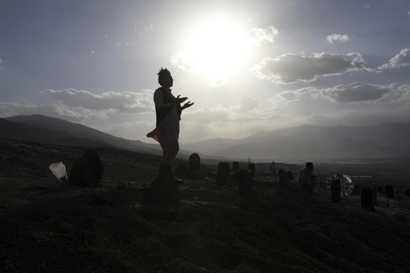 Afghan men prays near the grave of their relatives killed in bombings near Syed Al-Shahada School last month at cemetery on the outskirts of Kabul, Afghanistan, Wednesday, June 2, 2021. After the collapse of the Taliban 20 years ago, Afghanistan's ethnic Hazaras began to flourish and soon advanced in various fields, including education and sports, and moved up the ladder of success. They now fear those gains will be lost to chaos and war after the final withdrawal of American and NATO troops from Afghanistan this summer. (AP Photo/Rahmat Gul)