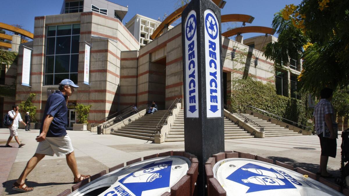 Pedestrians walk by a recycling bin on the UCLA campus.