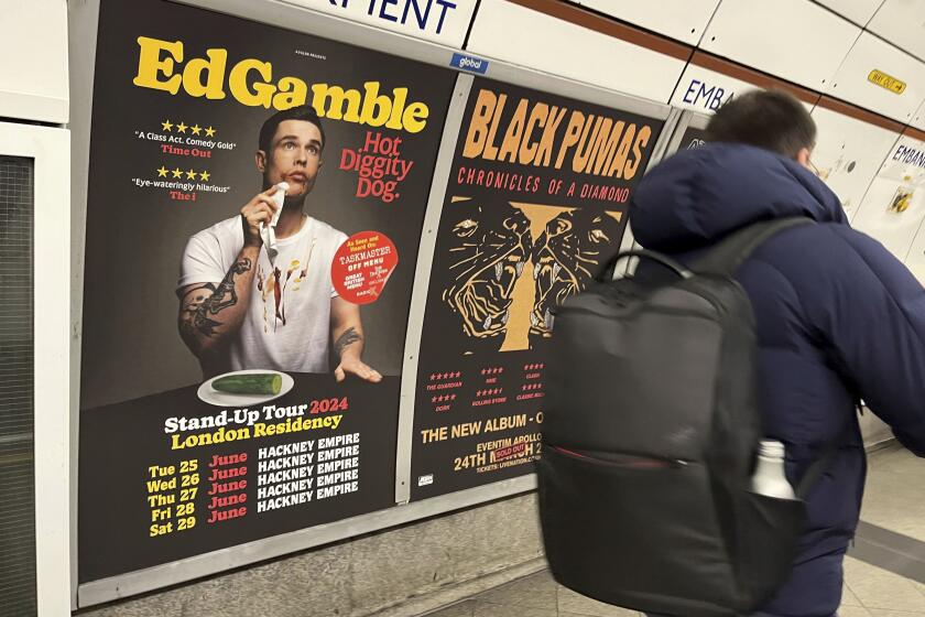 A view of a poster advertising comedian Ed Gamble's Hot Diggity Dog tour on the Bakerloo line platform at Embankment underground station in London, Wednesday March 27, 2024. Gamble has been ordered to change a subway station poster campaign for his new standup show because the image of a hot dog violated the transit network’s ban on junk food advertising. The poster for the show, “Hot Diggity Dog,” showed a mustard- and ketchup-smeared Gamble beside a half-eaten hot dog on a plate. A bemused Gamble replaced the wiener with a cucumber, and the poster was approved. (Joe Sene/PA via AP)