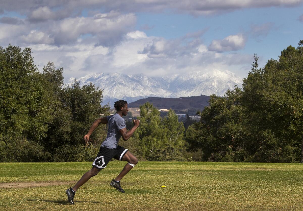 An athlete runs with snow-capped mountains in background 