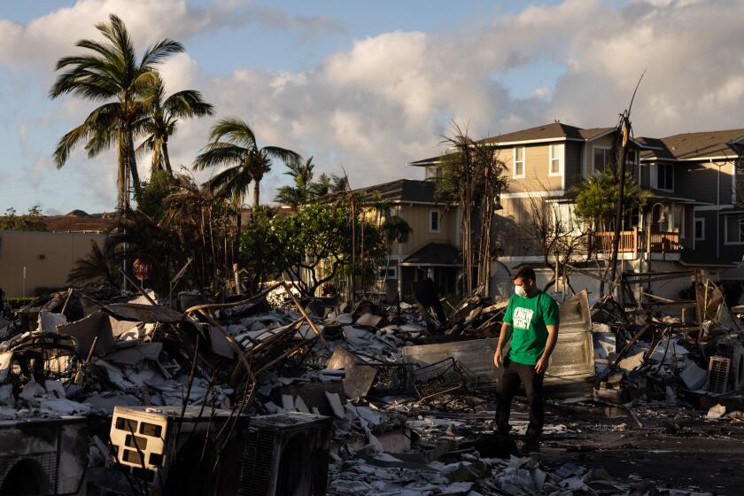 TOPSHOT - A Mercy Worldwide volunteer makes damage assessment of charred apartment complex in the aftermath of a wildfire in Lahaina, western Maui, Hawaii on August 12, 2023. Hawaii's Attorney General, Anne Lopez, said August 11, she was opening a probe into the handling of devastating wildfires that killed at least 80 people in the state this week, as criticism grows of the official response. The announcement and increased death toll came as residents of Lahaina were allowed back into the town for the first time. (Photo by Yuki IWAMURA / AFP) (Photo by YUKI IWAMURA/AFP via Getty Images)