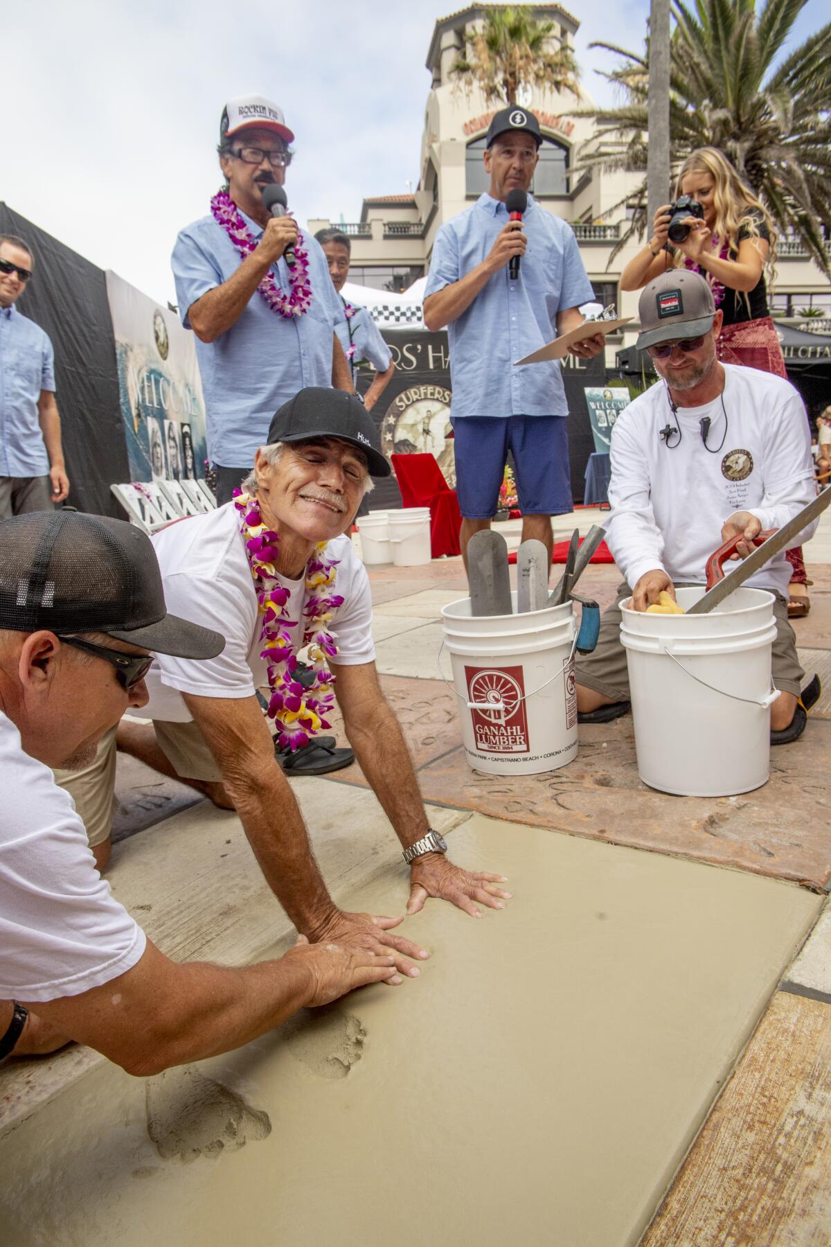 Sam Hawk, a surfer and surfboard shaper, plants his handprints in wet cement Friday during his induction into the Surfers' Hall of Fame in front of Huntington Surf and Sport on Main Street in Huntington Beach.