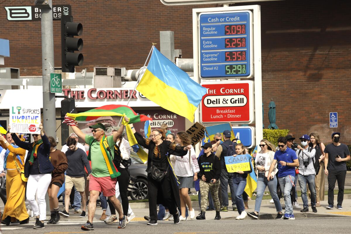 Pro-Ukraine demonstrators march past a gas station in Westwood featuring prices of more than $5 a gallon on Feb. 26.