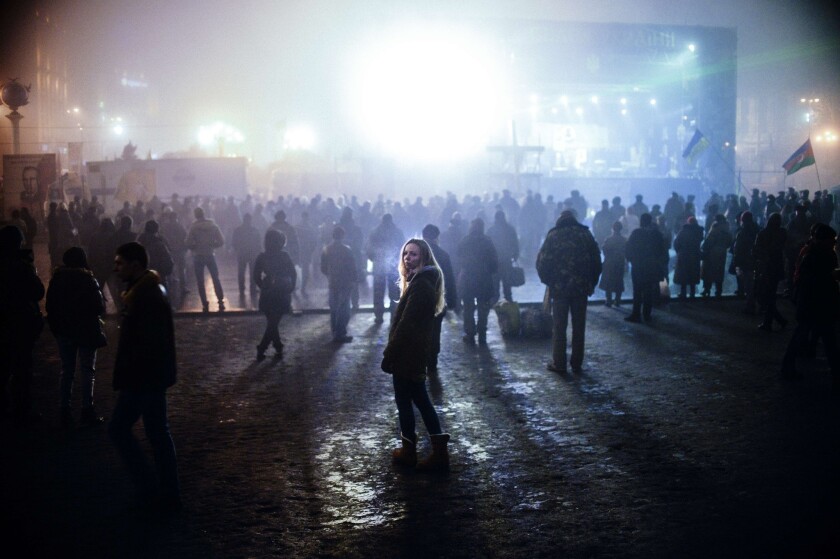 A woman looks on as people watch news on a large TV screen at Independence Square in central Kiev. Russian forces have surrounded Ukrainian military bases across Crimea as the Russian-speaking autonomous region has been thrown into turmoil following the ouster last month of Moscow-backed president Viktor Yanukovych.