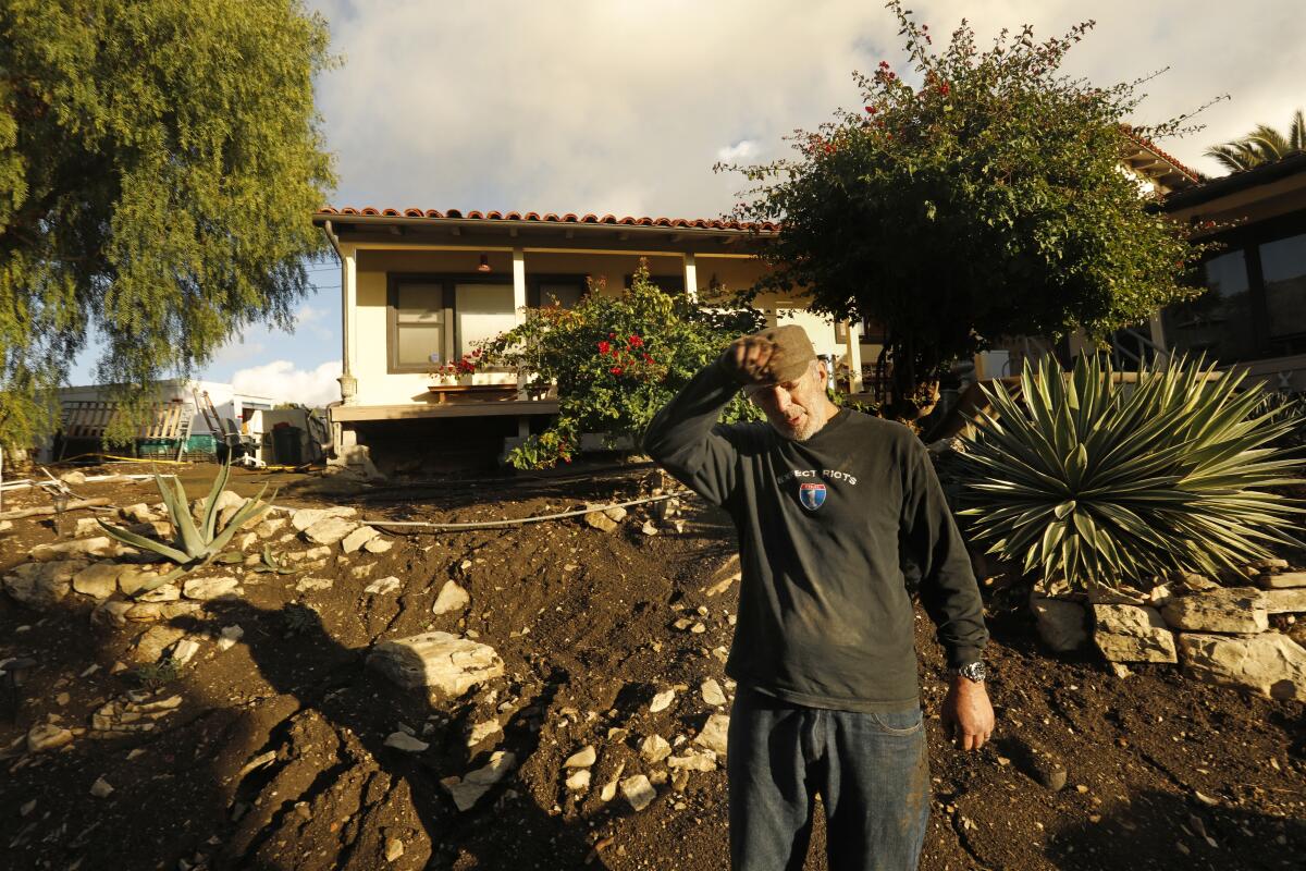 Peter James Cavanna stands outside a house on dirt.