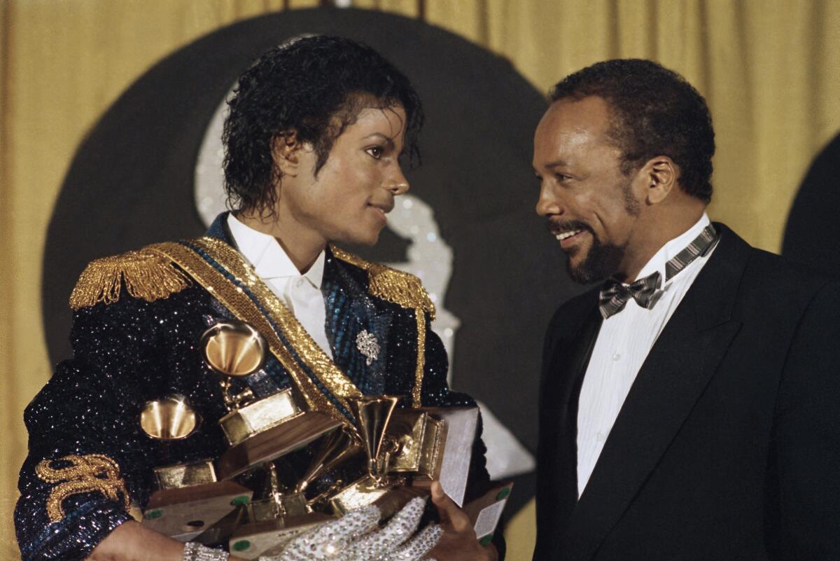 Michael Jackson is shown in 1984 holding his many awards as he speaks with Quincy Jones at the Grammy Awards. The year before, David Bowie put MTV on the spot for featuring so few black artists.