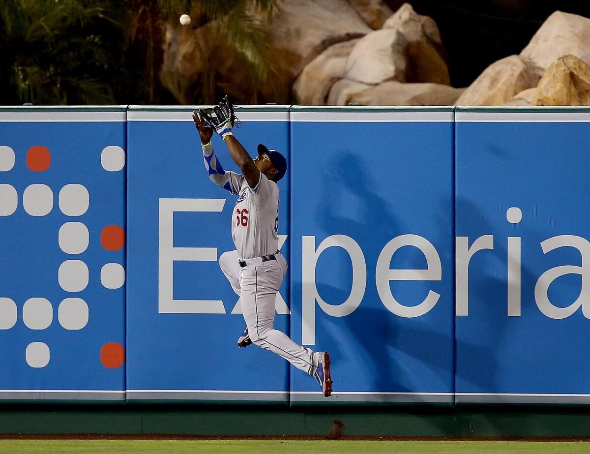 Dodgers outfielder Yasiel Puig rises up to rob Angels outfielder Josh Hamilton of an extra-base hit in the sixth inning of a game Thursday at Angel Stadium.