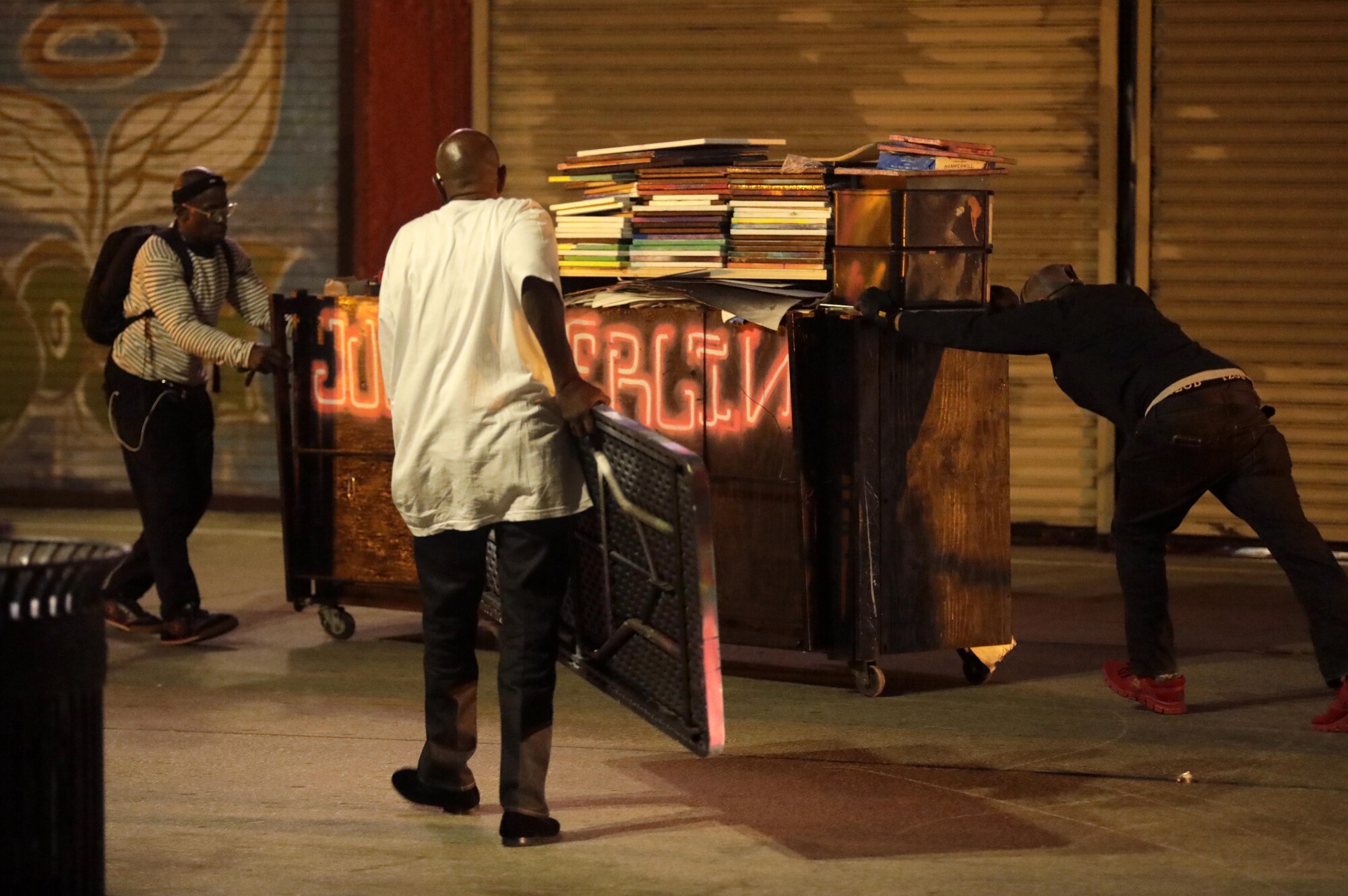 Jules Navarro, right, pushes his belongings with the help of friends.