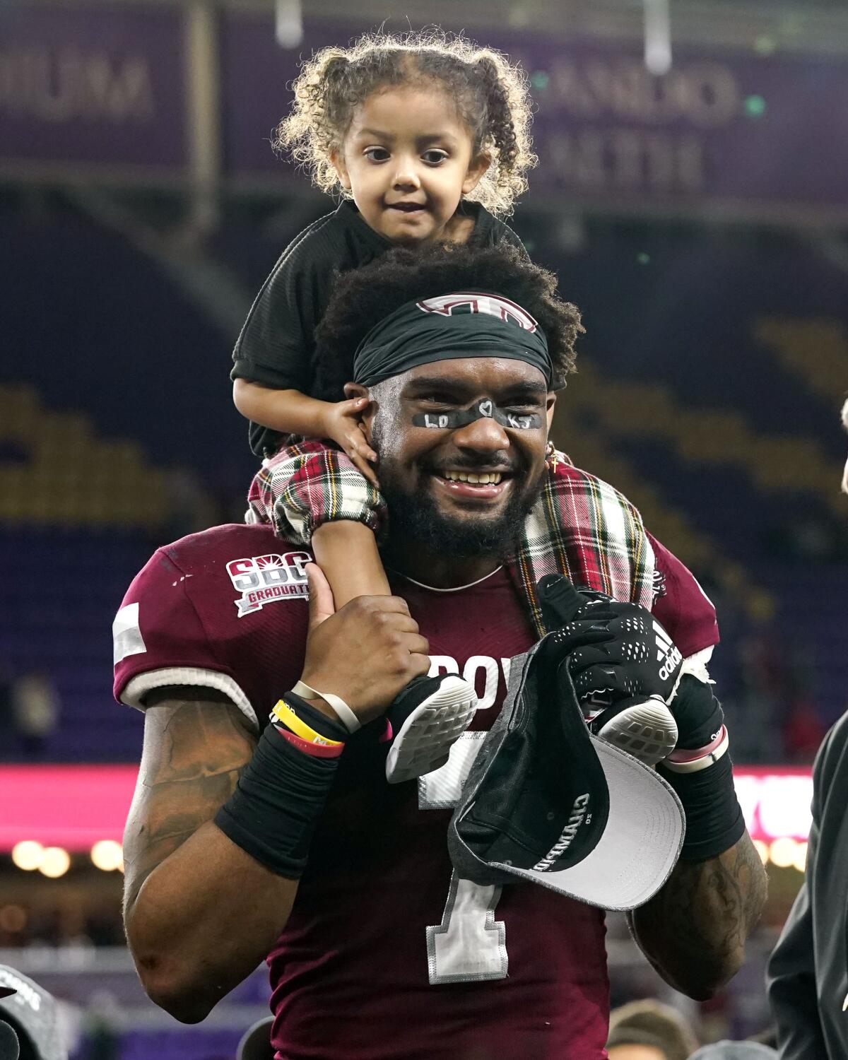 Troy linebacker K.J. Robertson hoists his daughter Layla, 2, after he was named MVP of the Cure Bowl.