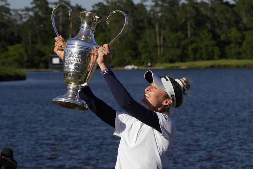 Nelly Korda holds up the trophy while celebrating her win at the Chevron Championship.