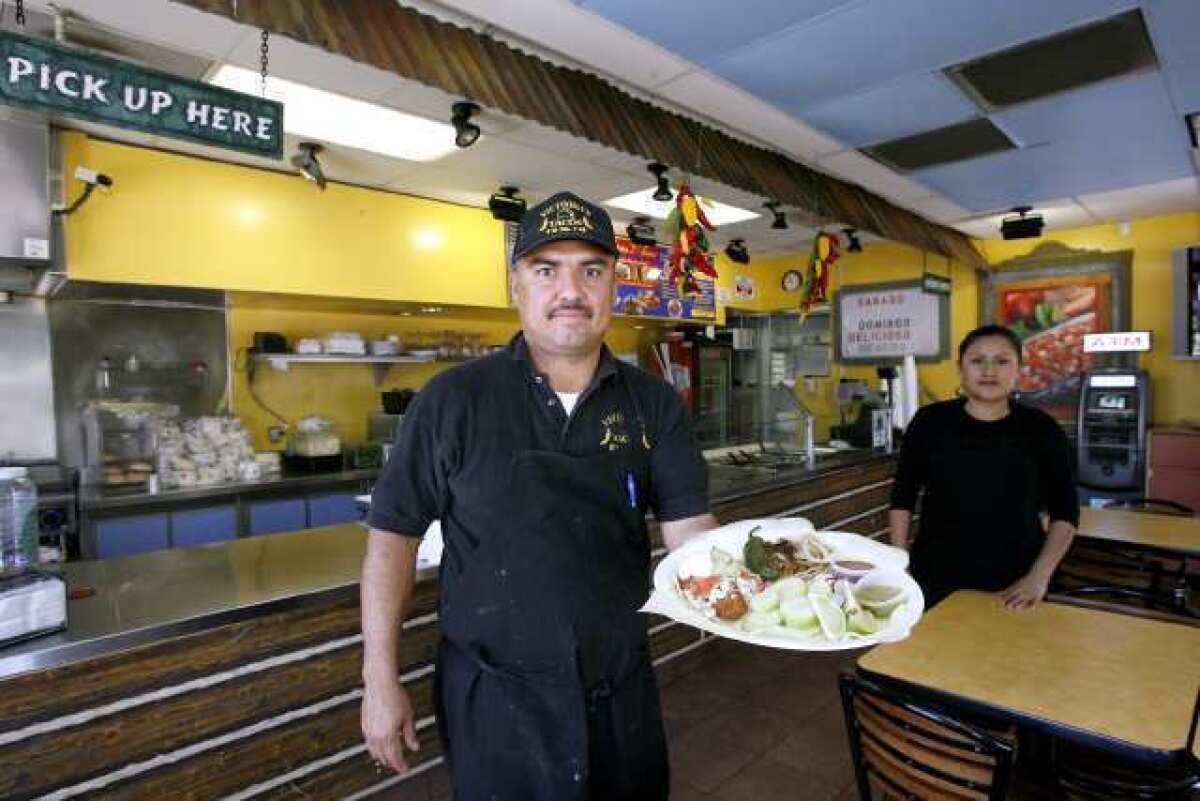 Leonardo Sandoval from Victoria's Tacos & Grill holds the fish taco, with Beatriz Lopez in the background, on the 4200 block of San Fernando Road in Glendale.