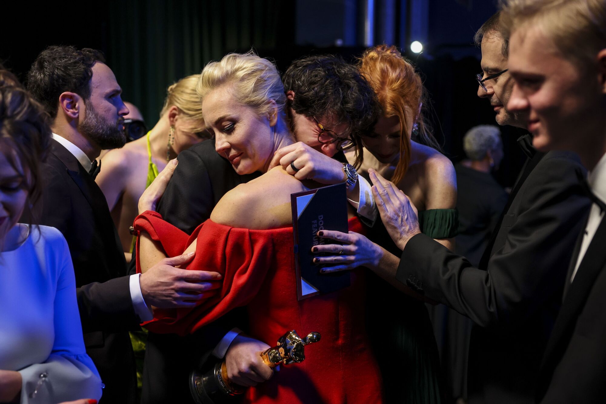 A man and a woman embrace amid a crowd backstage at the 95th Academy Awards at the Dolby Theatre.