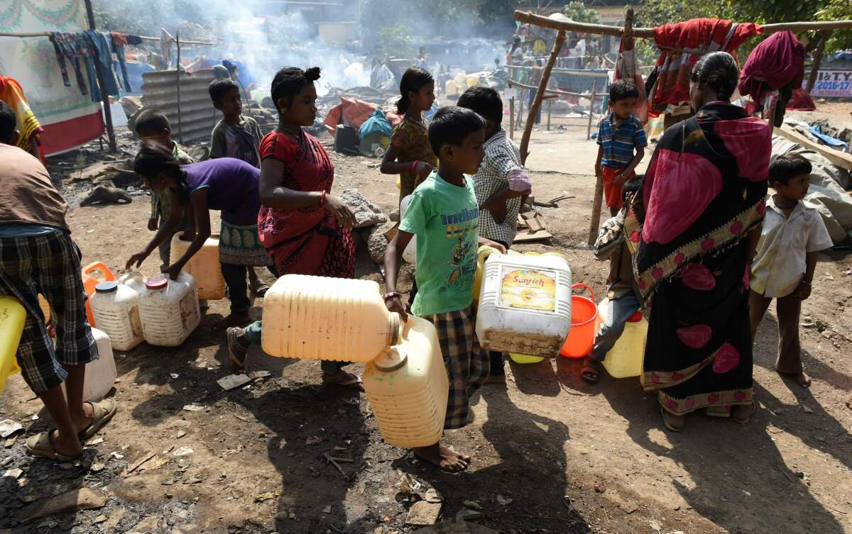 Indian villagers stand in a line for potable water at a makeshift camp in Mumbai on April 28.