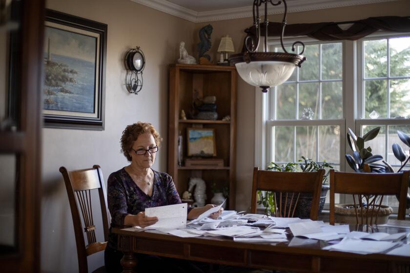 Janet Uhlar sits at her dining room table with letters and photos she received through her correspondence with imprisoned Boston organized crime boss James "Whitey" Bulger, Friday, Jan. 31, 2020, in Eastham, Mass. Although much had been written about the CIA's mind control experiments before Bulger's trial, Uhlar said she knew nothing about them until she began corresponding with the renowned gangster following his conviction in the fall of 2013. (AP Photo/David Goldman)