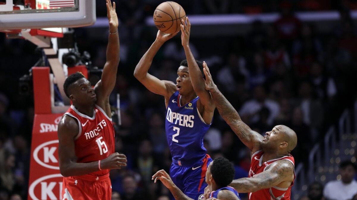 Clippers guard Shai Gilgeous-Alexander looks to pass against the double-team defense of Rockets center Clint Capela (15) and guard Eric Gordon during their game Oct. 21.