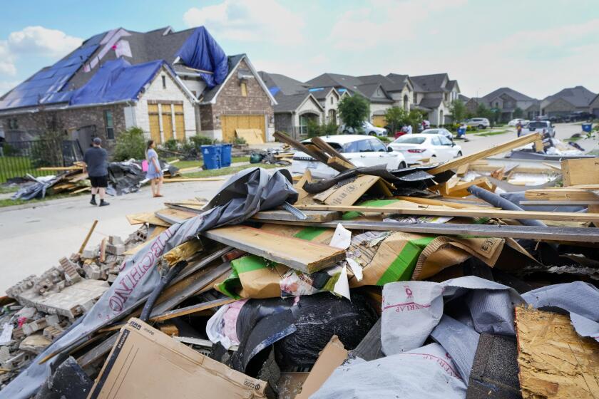 People walk through a Bridgeland neighborhood as families begin cleaning up storm damage, Sunday, May 19, 2024, in Cypress, Texas. (Brett Coomer/Houston Chronicle via AP)