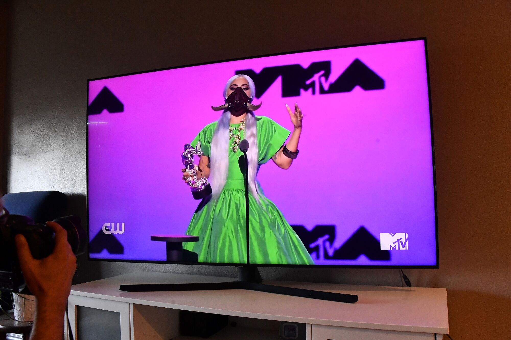 Lady Gaga, photographed on screen, accepts an award at the 2020 VMAs.