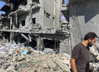 A man walks through the ruins of buildings.