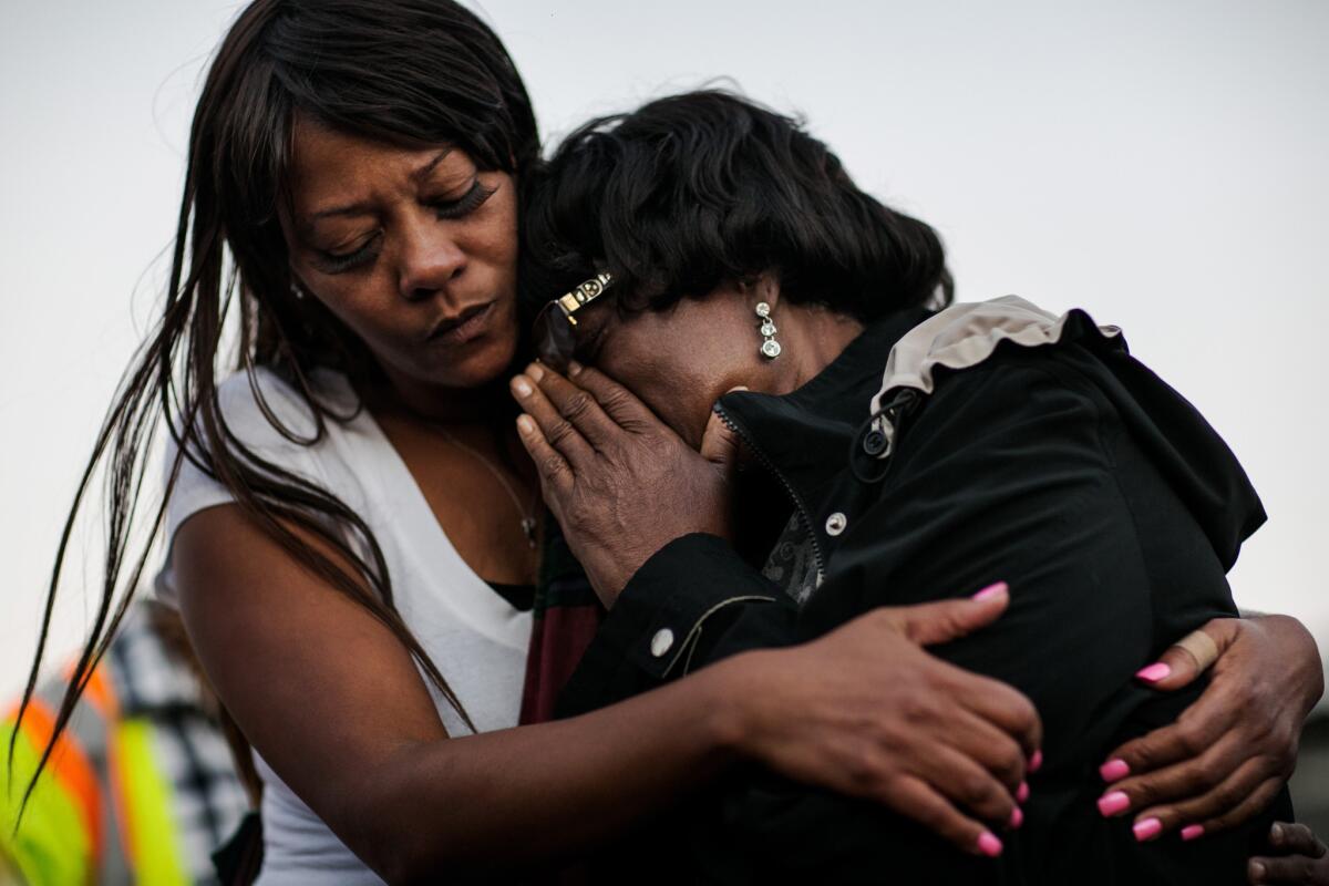 Catherine Mazzucco, right, mother of Marcus McClendon, 52, breaks down during a vigil at the spot where McClendon was shot.
