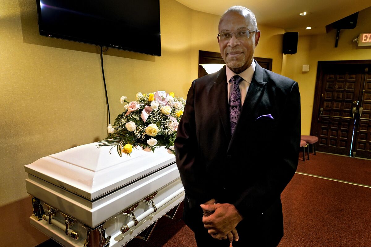 Wayne Bright, funeral director at Wilson Funeral Home poses for a photo in a viewing room before a service Thursday, Sept. 2, 2021, in Tampa, Fla. Bright has seen grief piled upon grief during the latest COVID-19 surge as Florida is in the grip of its deadliest wave since the pandemic began, a disaster driven by the highly contagious delta variant. (AP Photo/Chris O'Meara)