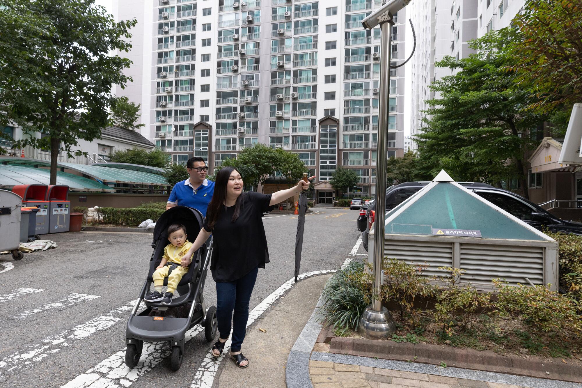 A couple walk down the street with a baby in a stroller 