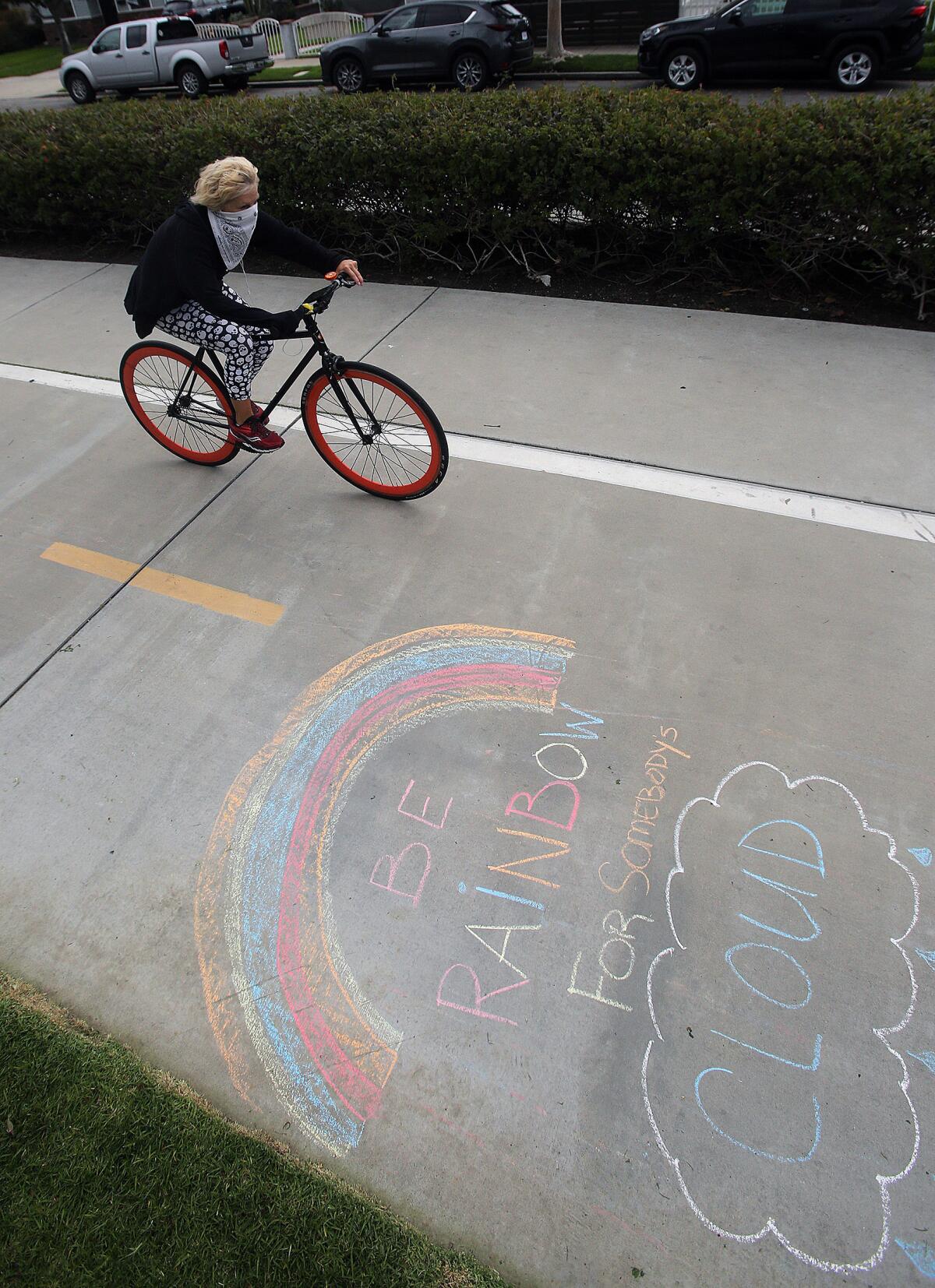 A cyclist passes a chalked rainbow on the Chandler Bikeway in Burbank on Tuesday, March 24, 2020. The bikeway is popular for people after gyms, hiking trails, beaches, entertainment venues and more have been recently closed due to the coronavirus.
