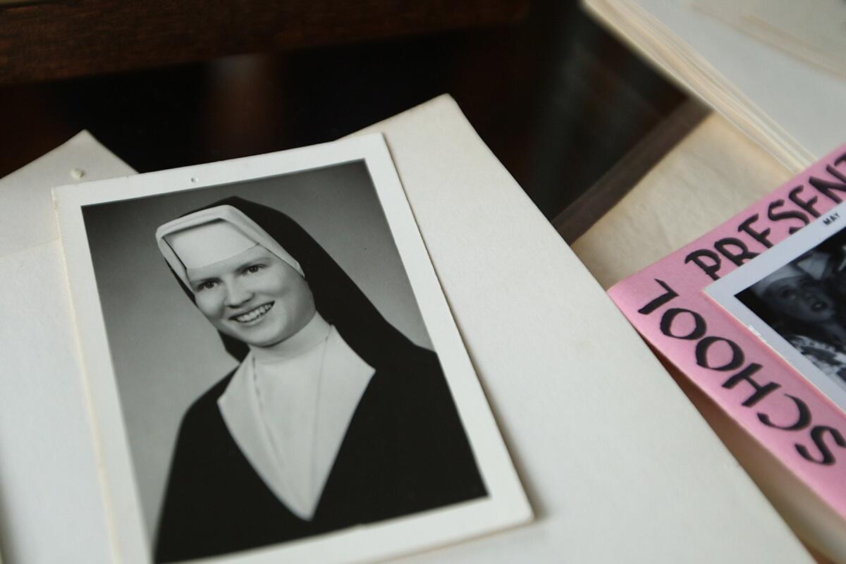 A black-and-white photo of a nun among sheets of paper.
