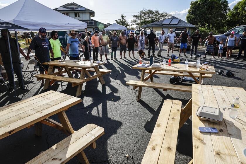 Lahaina, Maui, Monday, August 14, 2023 - Lahaina residents and volunteers join hands in prayer at an aid distribution center on Wahinoho Way. (Robert Gauthier/Los Angeles Times)