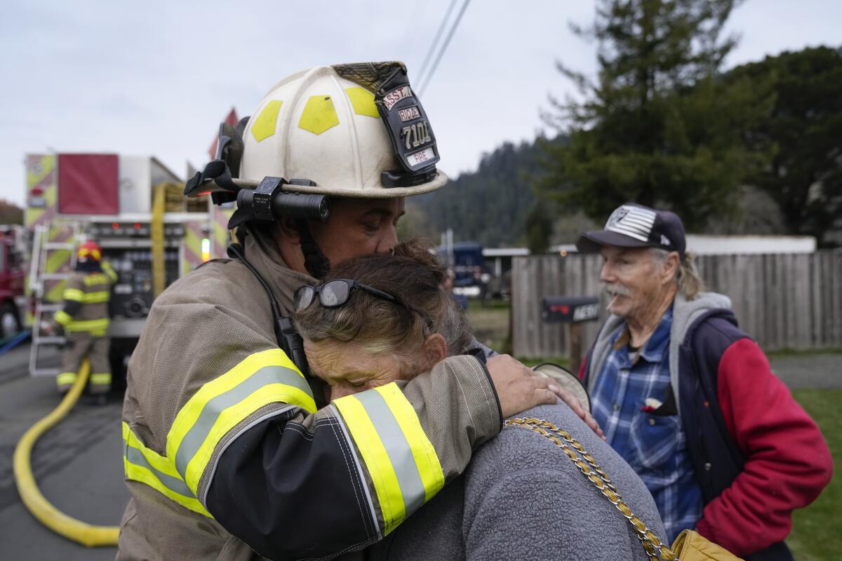 Ryan Heussler, the Rio Dell assistant fire chief, left, hugs a woman named Patty.
