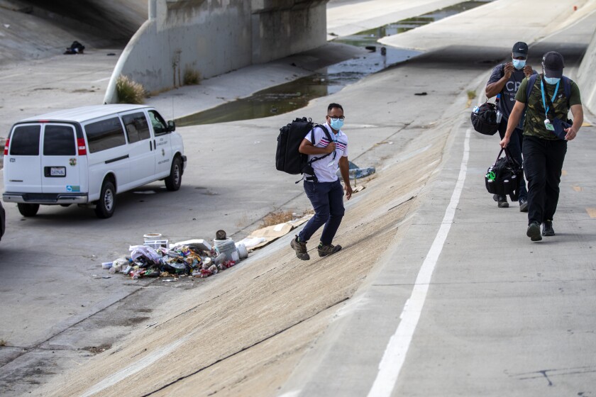 Three people walking up an embankment next to the La Canada Verde Creek