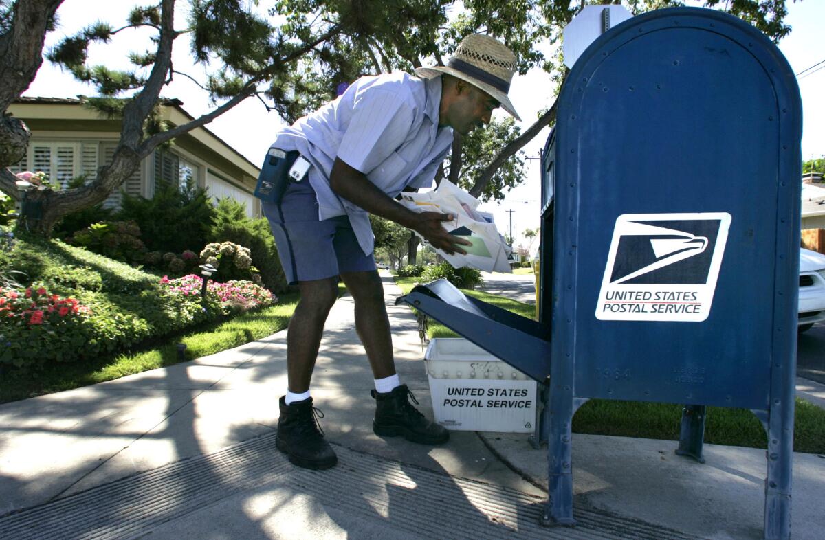 A U.S. Postal Service worker retrieves mail from a mailbox.