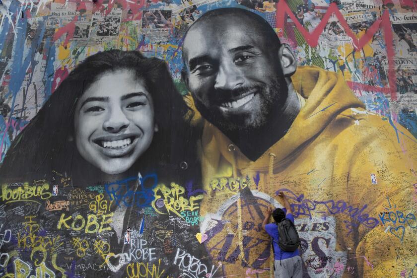 LOS ANGELES, CA-FEBRUARY 27, 2020: Ernest Wilson of Dallas, Texas writes a message on a mural honoring Los Angeles Lakers legend Kobe Bryant and his daughter Gianna, located on the exterior wall of a building on the 1200 block of South La Brea Ave. in Los Angeles. Mike Asner, a lifelong Los Angeles Lakers fan, created a website and Instagram account to track the locations of all the murals honoring Kobe Bryant. So far, he's cataloged more than 120 murals around Southern California, mostly in Los Angeles and Orange County, plus multiple other locations around the world on his website KobeMural.com. (Mel Melcon/Los Angeles Times)