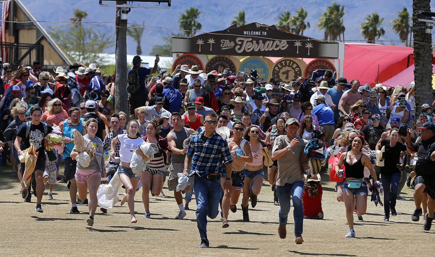 Country music fans dash out from behind gates to get the best concert viewing seats as they arrive on the second day of the 10th edition of Stagecoach Country Music Festival at the Empire Polo Club in Indio on April 30.