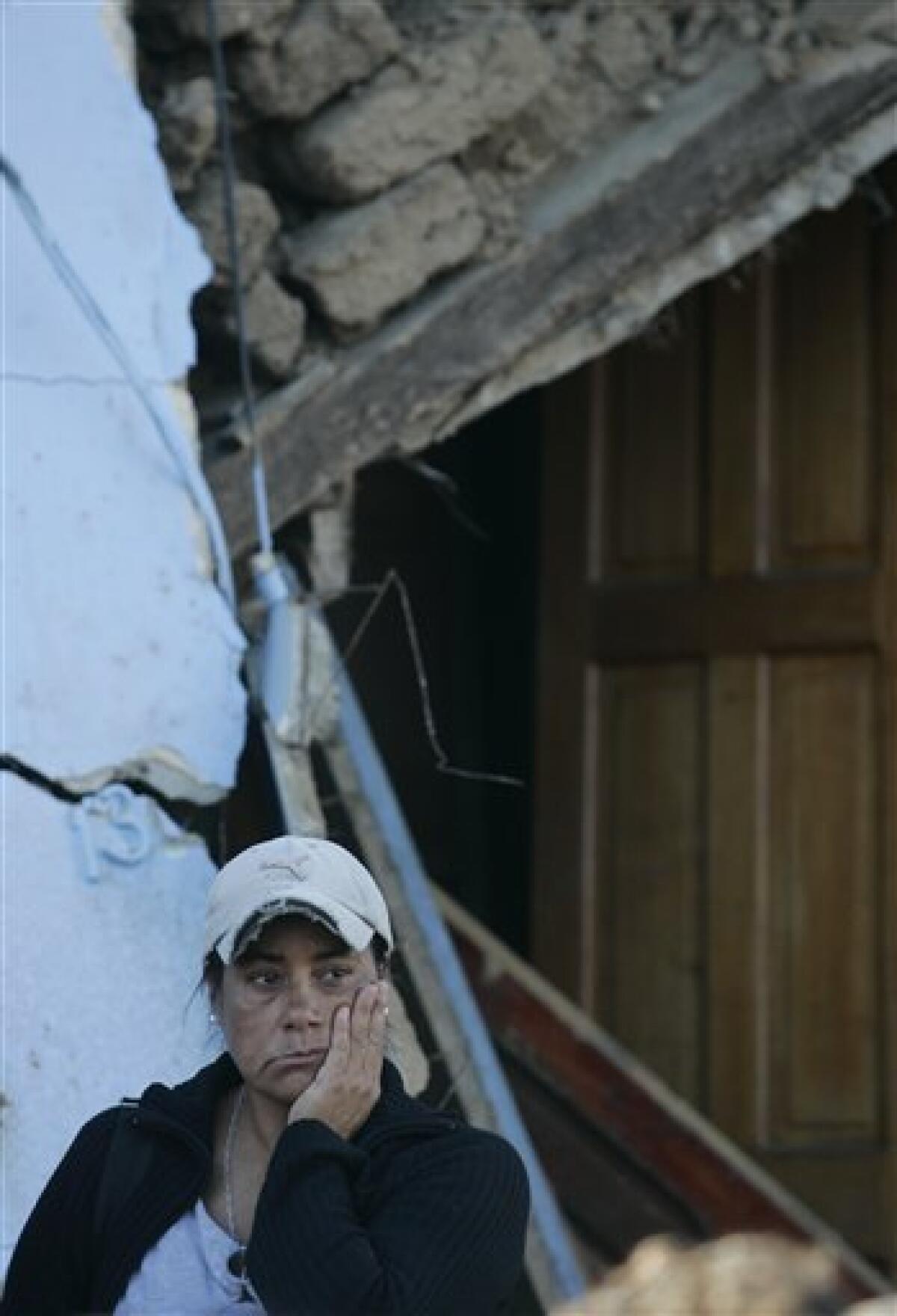 A woman gestures in front of an earthquake damaged house in Constitucion, Chile, Monday, March 8, 2010. An 8.8-magnitude earthquake hit central Chile last Feb. 27, causing widespread damage. (AP Photo/Fernando Vergara)