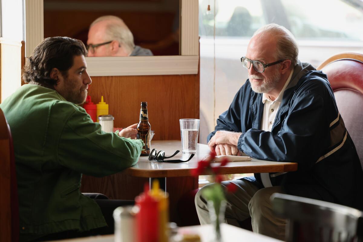 Two men sit in a booth in a restaurant.