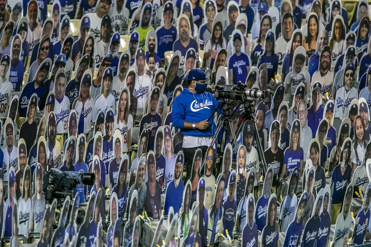 A camera operator works amid a sea of cardboard fans at Dodger Stadium