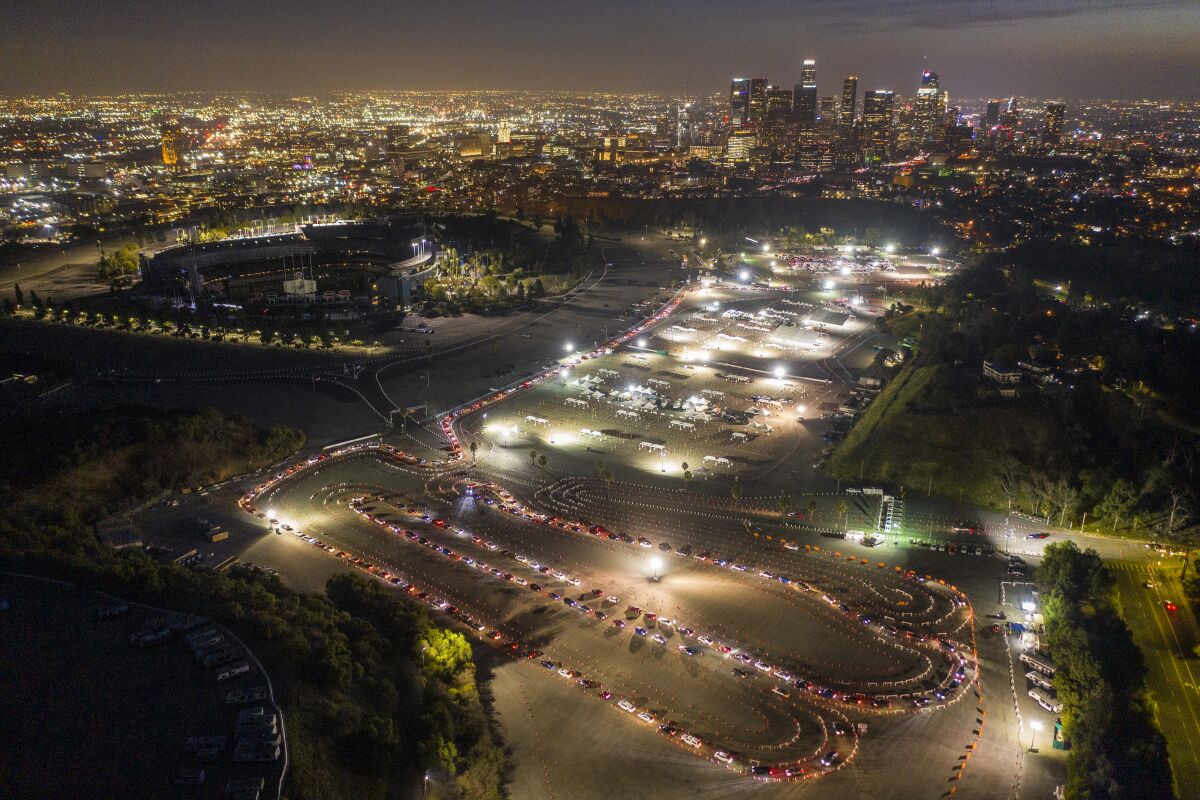 Aerial view of long line of cars snaking through Dodger Stadium parking lot at night