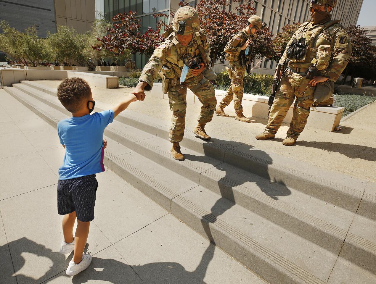 A boy fist-bumps a National Guardsman at LAPD headquarters.