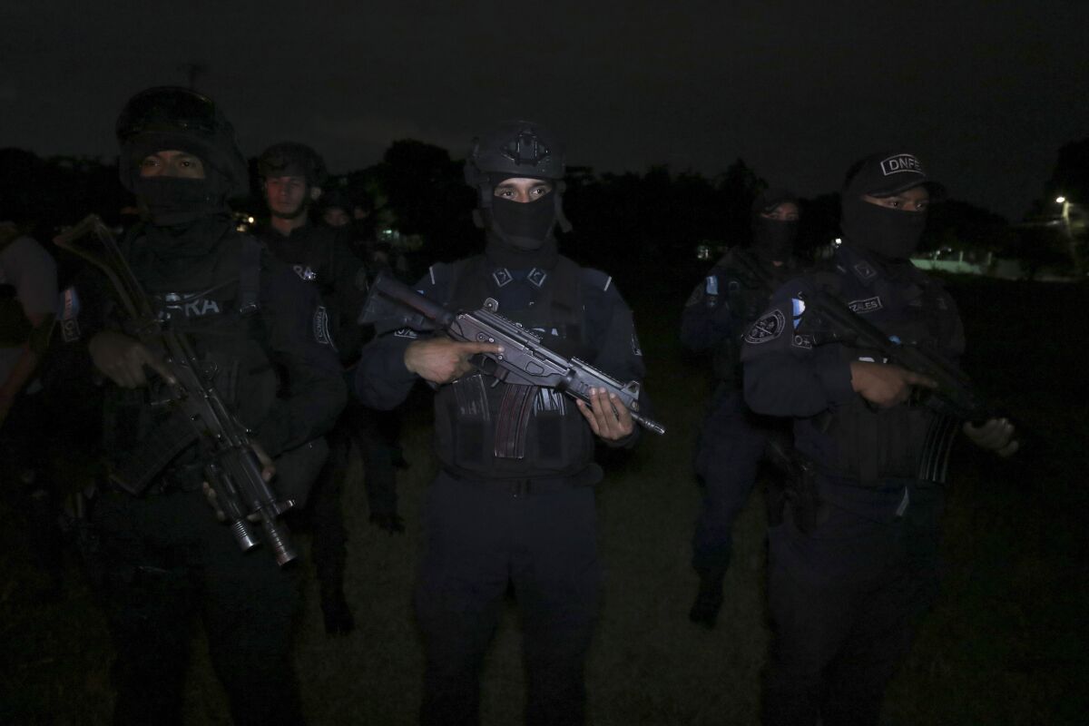Saldırı silahları kullanan koyu renkli üniformalı bir grup subay