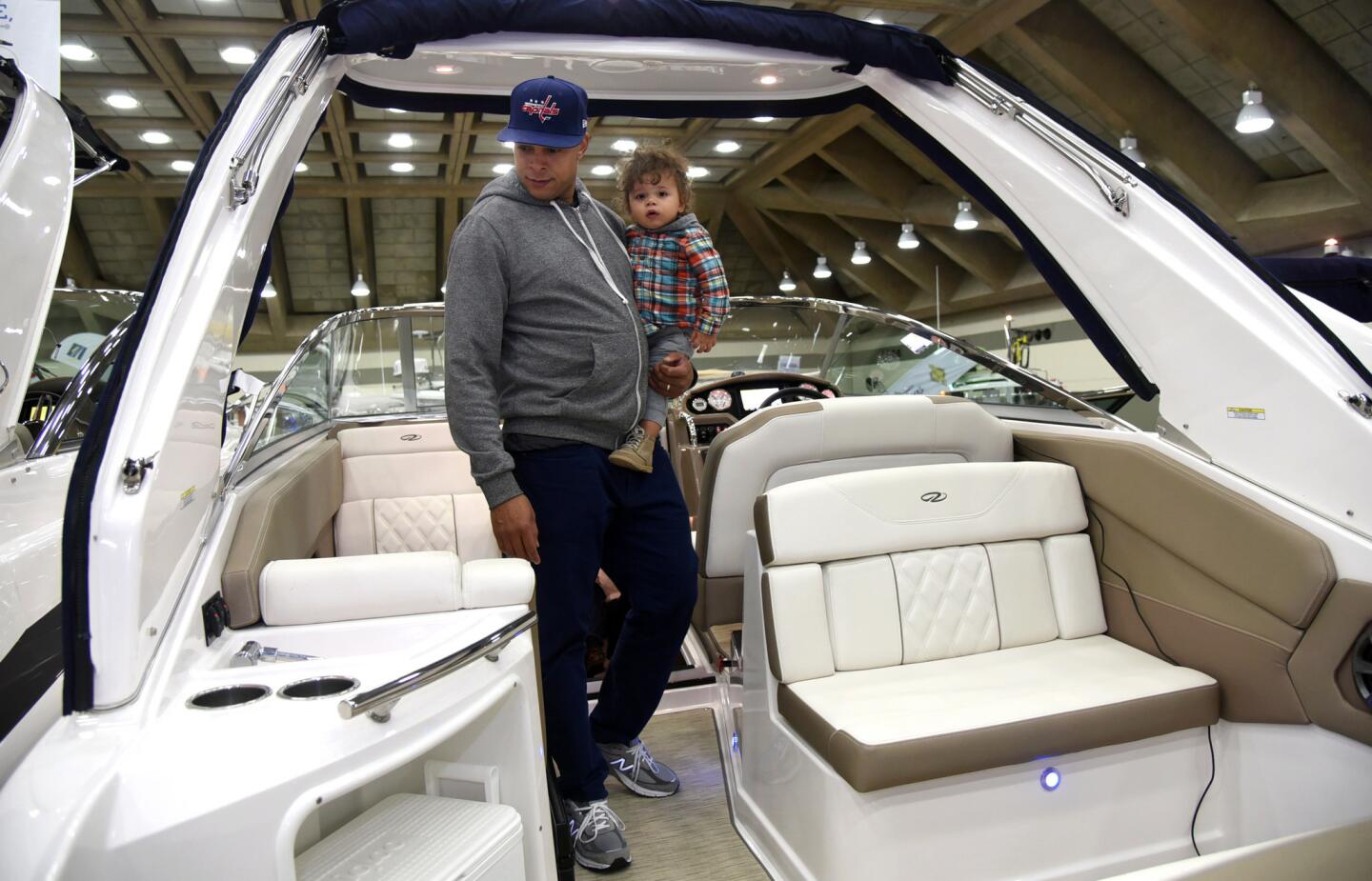Jason Lallis of Washington DC holds his 16 month old son Jordan Lallis as they look at a Regal Express cruiser at the Baltimore Boat Show, which is being held this weekend at the Baltimore Convention Center.