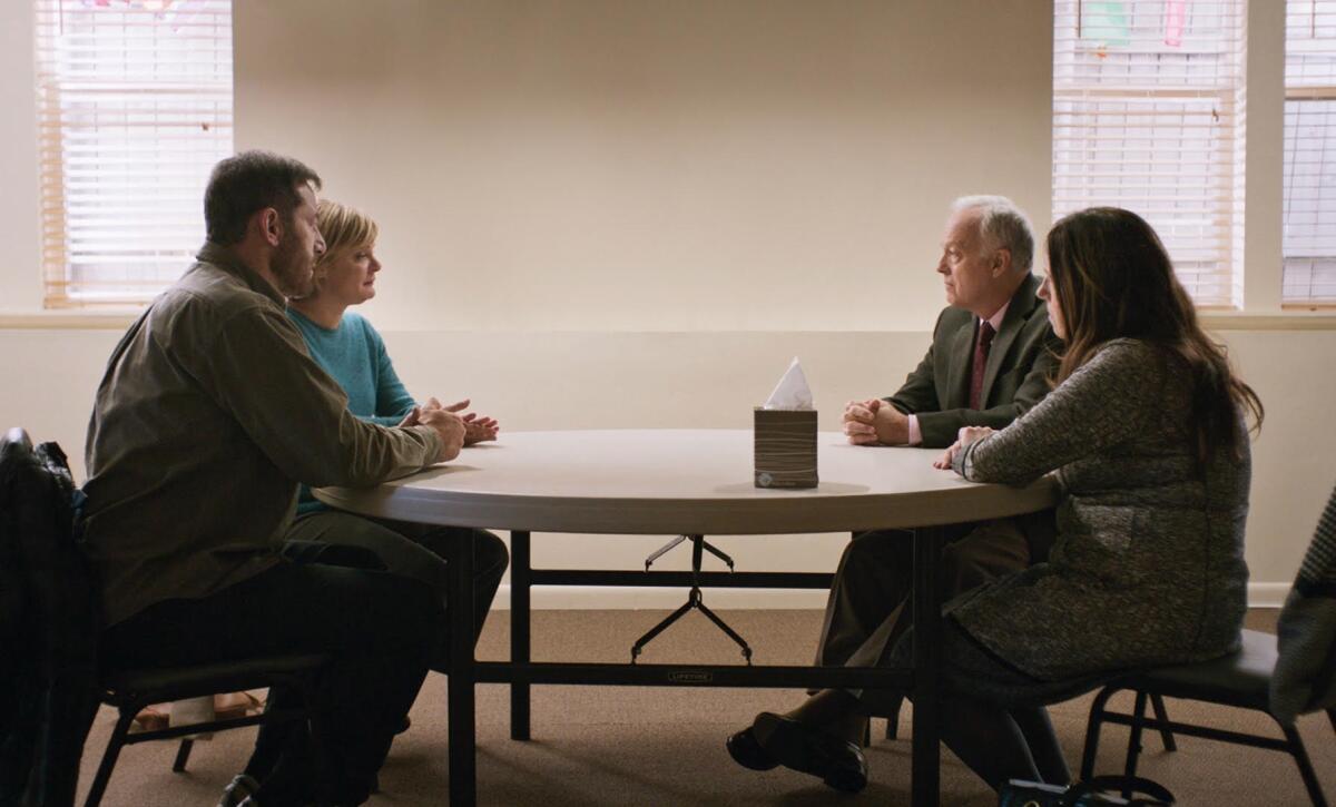 Two couples face sit facing each other around a table in the movie "Mass."