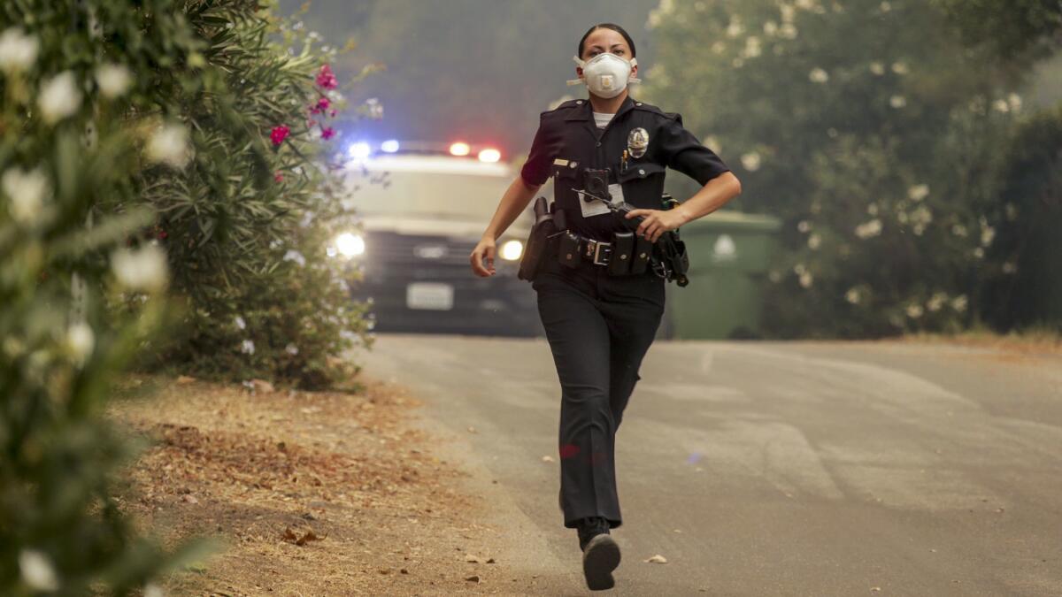 A police officer runs to evacuate residents as the La Tuna fire approaches homes in Sunland. f