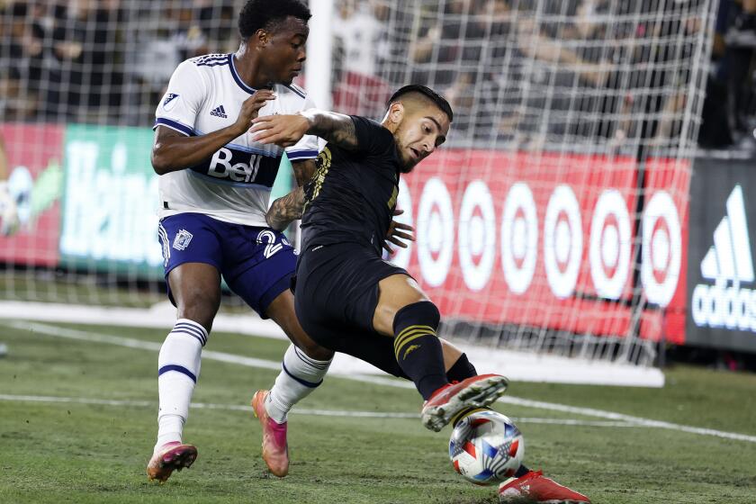 Los Angeles FC forward Cristian Arango, right, controls the ball while defended by Vancouver Whitecaps defender Javain Brown during the first half of an MLS soccer match Tuesday, Nov. 2, 2021, in Los Angeles. (AP Photo/Ringo H.W. Chiu)