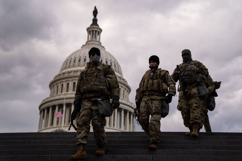 WASHINGTON, DC - JANUARY 18: National Guard Troops from Virginia walk down the stairs towards the Capitol Visitors Center on Monday, Jan. 18, 2021 in Washington, DC. After last week's riots and security breach at the U.S. Capitol Building, the FBI has warned of additional threats in the nation's capital and across all 50 states. (Kent Nishimura / Los Angeles Times)