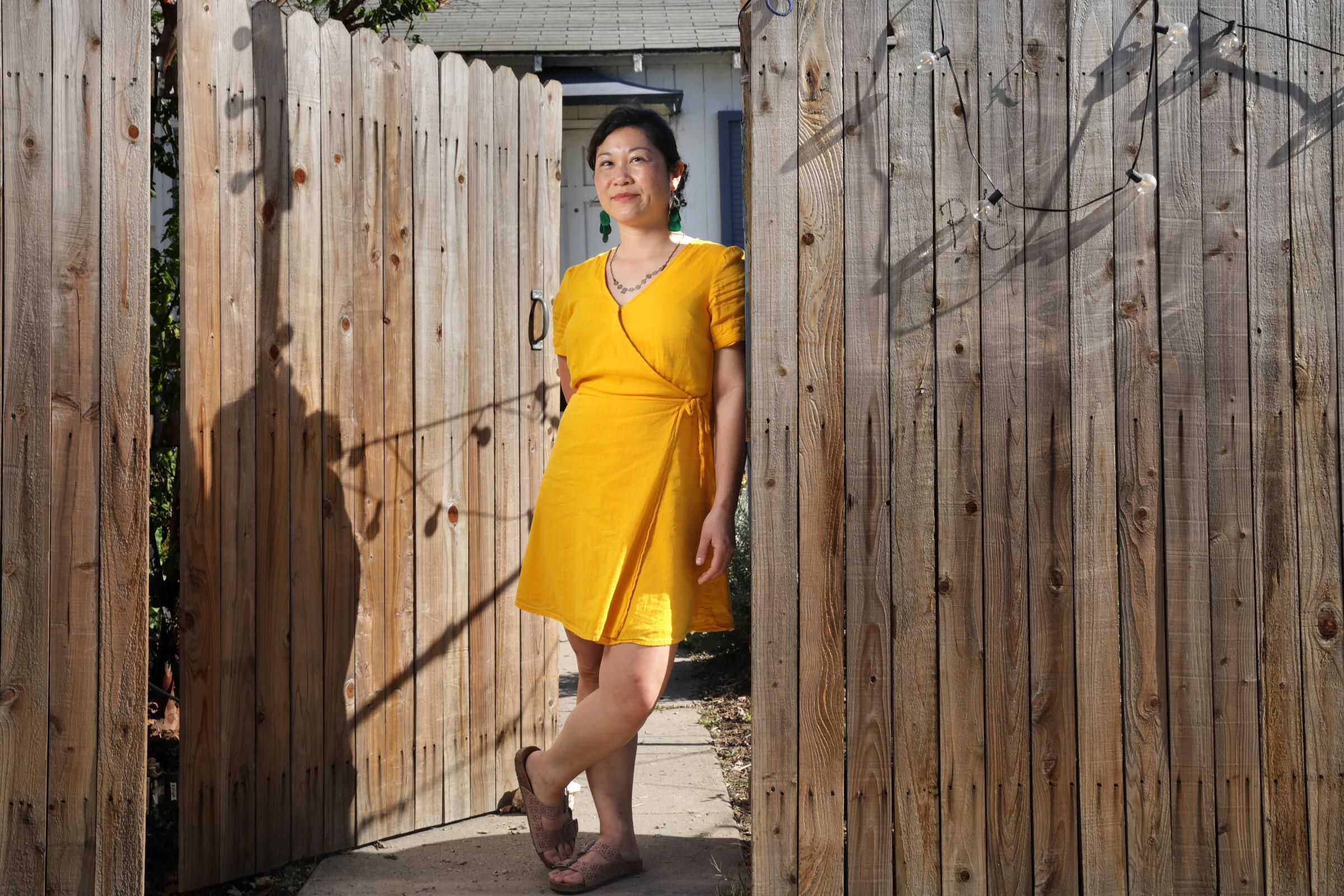 A woman leans against a wooden fence